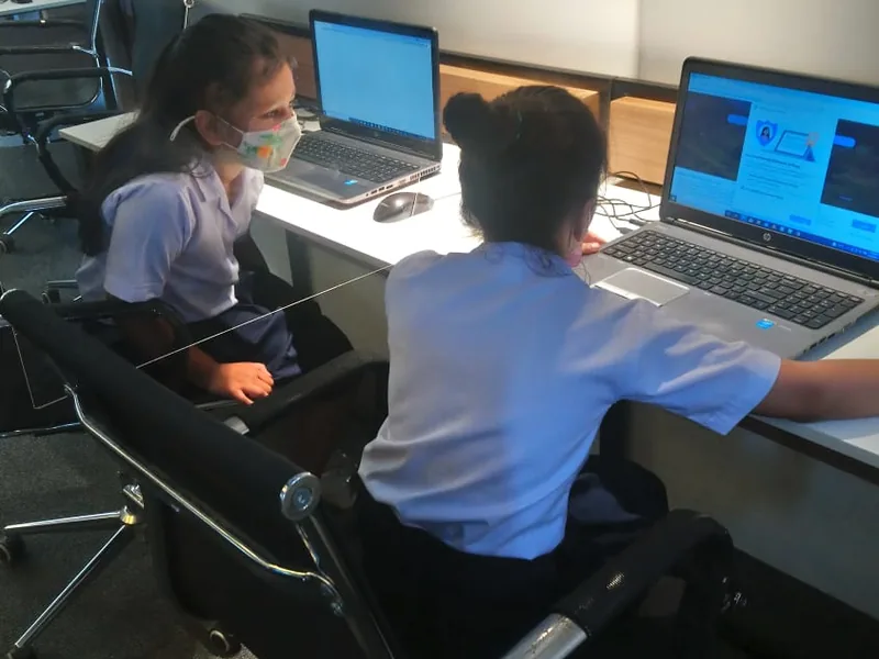 Two students coding on laptops