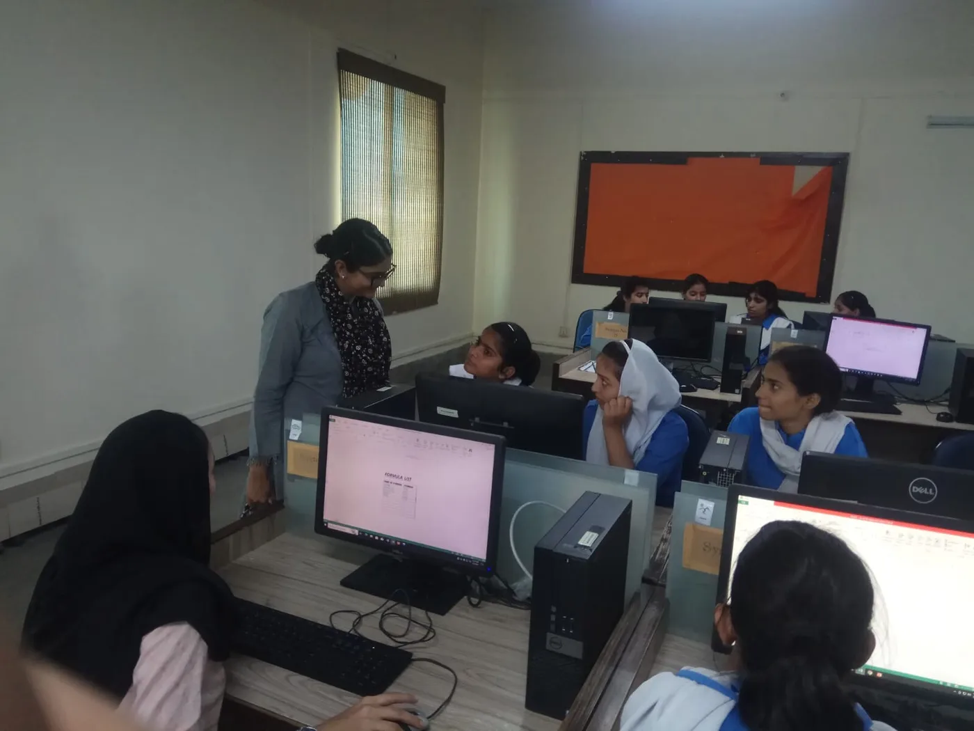 An observer reviewing students’ work at their computers