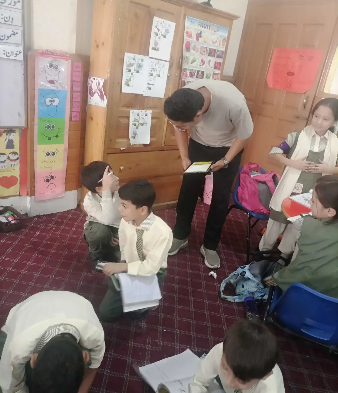An assessor checking young students' work in their classroom