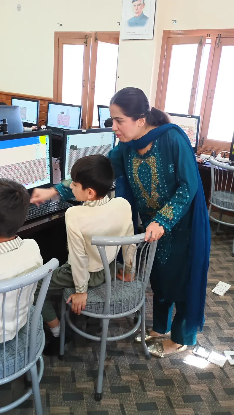A teacher guiding a student at a computer during a class observation