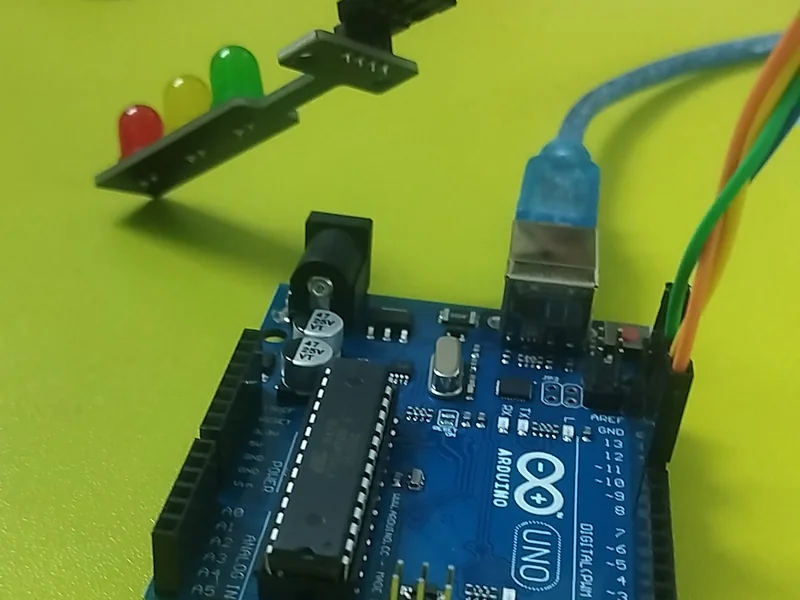 An Arduino board wired to a red, yellow and green traffic-light module